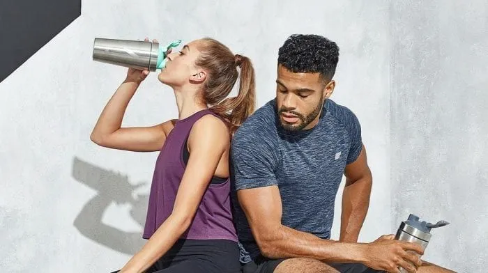 Sportler bereitet veganen Proteinshake nach dem Training zu. Bild veranschaulicht Anwendung und Dosierung von pflanzlichem Proteinpulver.